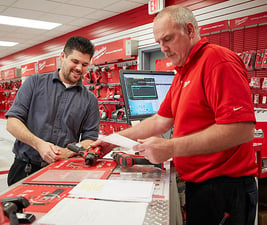 Two men at check out counter looking at tools